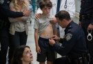 While playing at the park, my best friend’s son fell and broke his arm, so I rushed him to the ER. Just as I paid the hospital bill, the police handcuffed me. “You’re under arrest for child abuse.” My friend stood there sobbing, swearing she saw me deliberately push her son. I was completely frozen—until the doctor carried the boy out. Trembling, the little boy gripped the doctor’s coat, looked at the police, and whispered: “Officer… please take off my undershirt.”